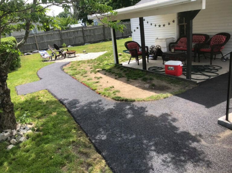 asphalt pathway around a patio in the backyard of a house